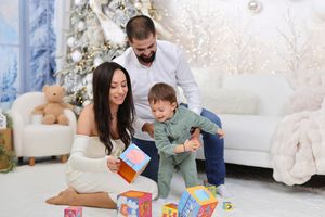 Family playing and reading together during holiday season with festive decorations in a cozy home setting.