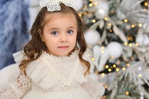 Winter portrait session with white Christmas decor and soft lighting.