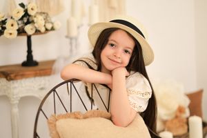 Studio portrait featuring delicate floral decor and vintage-style props in soft beige tones.