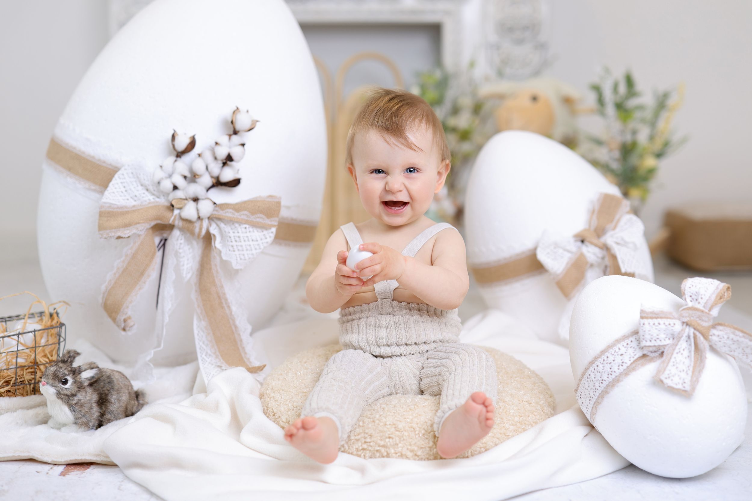 Easter-themed white studio setup with cotton balls and bunny decorations in pastel colors.