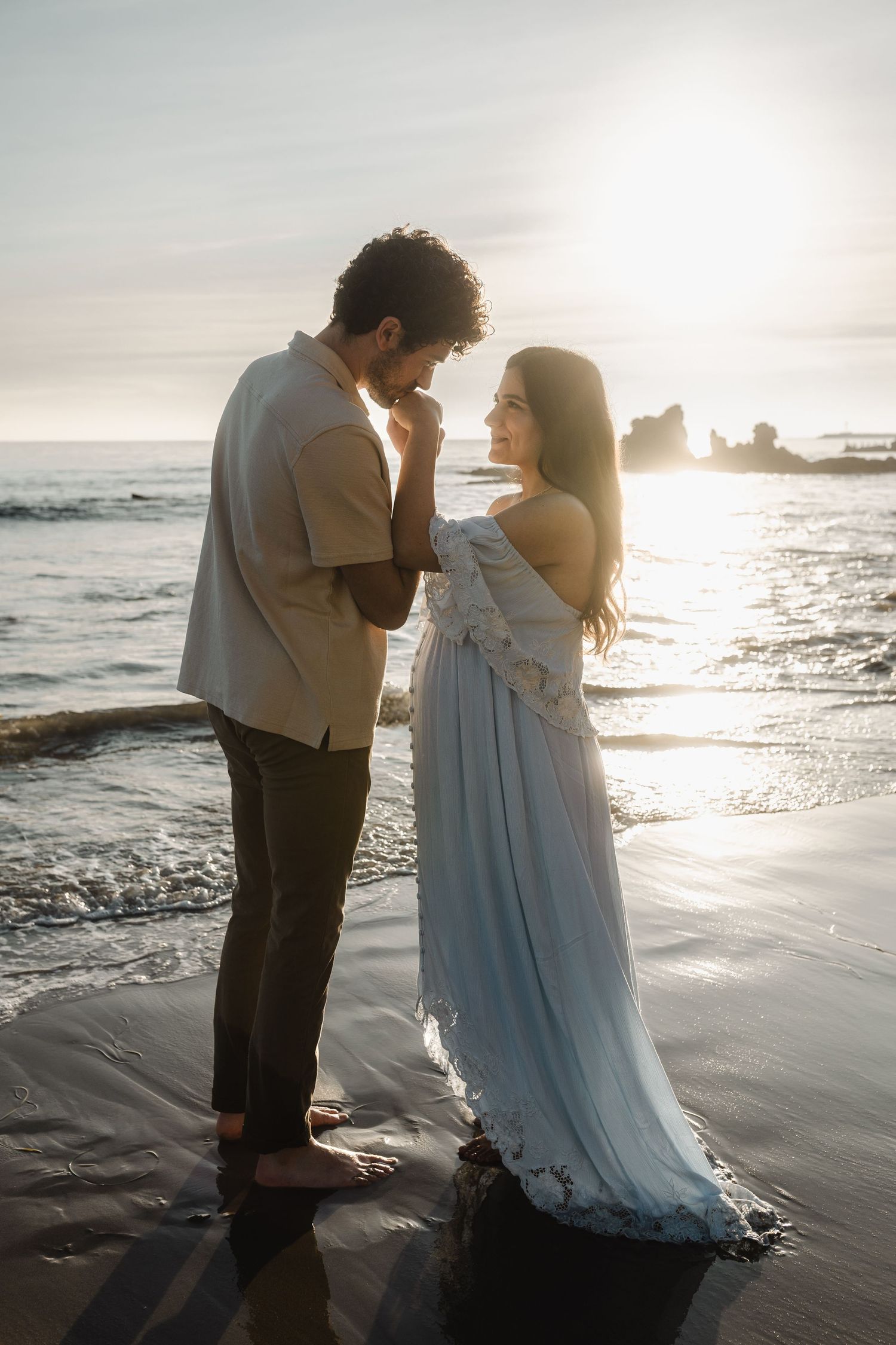 Romantic sunset beach photo shoot with couple in elegant attire.