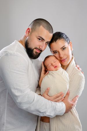 A couple in white clothing embraces tenderly against a light gray background in a series of intimate poses.