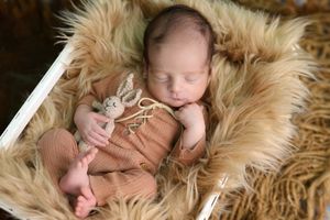 Baby sleeping on soft beige fur blanket in artistic newborn photography.