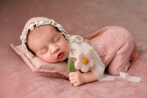 Series of delicate newborn photography poses on soft pink fabric with floral accents.