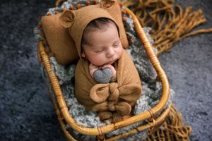 Baby sleeping in wicker basket wearing cute bear outfit with fuzzy ears.