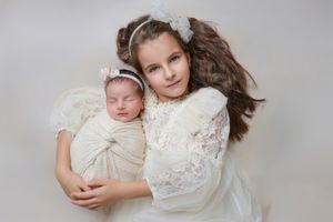 A split panel shows tender moments of a baby wearing a white dress with their caregiver against a neutral gray backdrop.