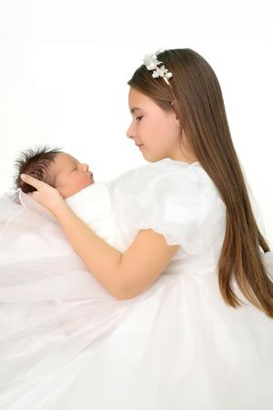 Side profile view of woman in white dress tenderly holding sleeping baby.