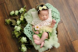 Baby photography with floral arrangements and mint green accessories on wooden floor.