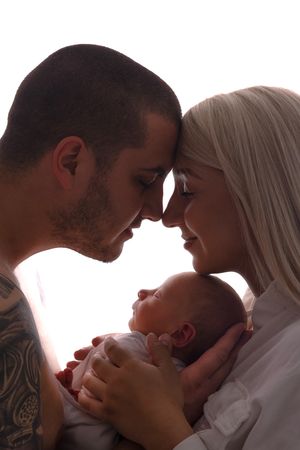 Intimate silhouette portrait of couple holding newborn baby against white background.