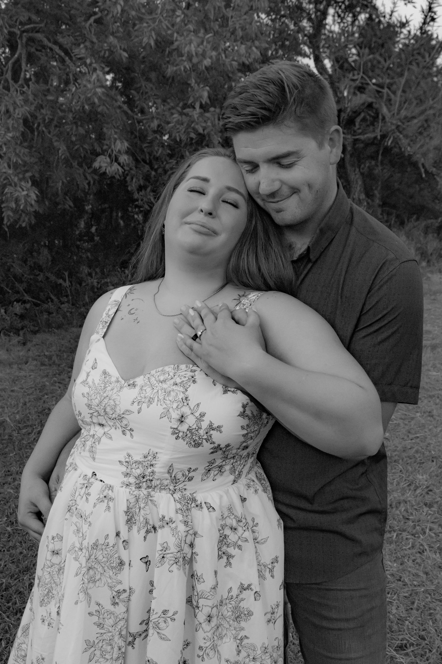 A romantic black and white wedding photo shows couple nestled together in an intimate embrace under flowing fabric.