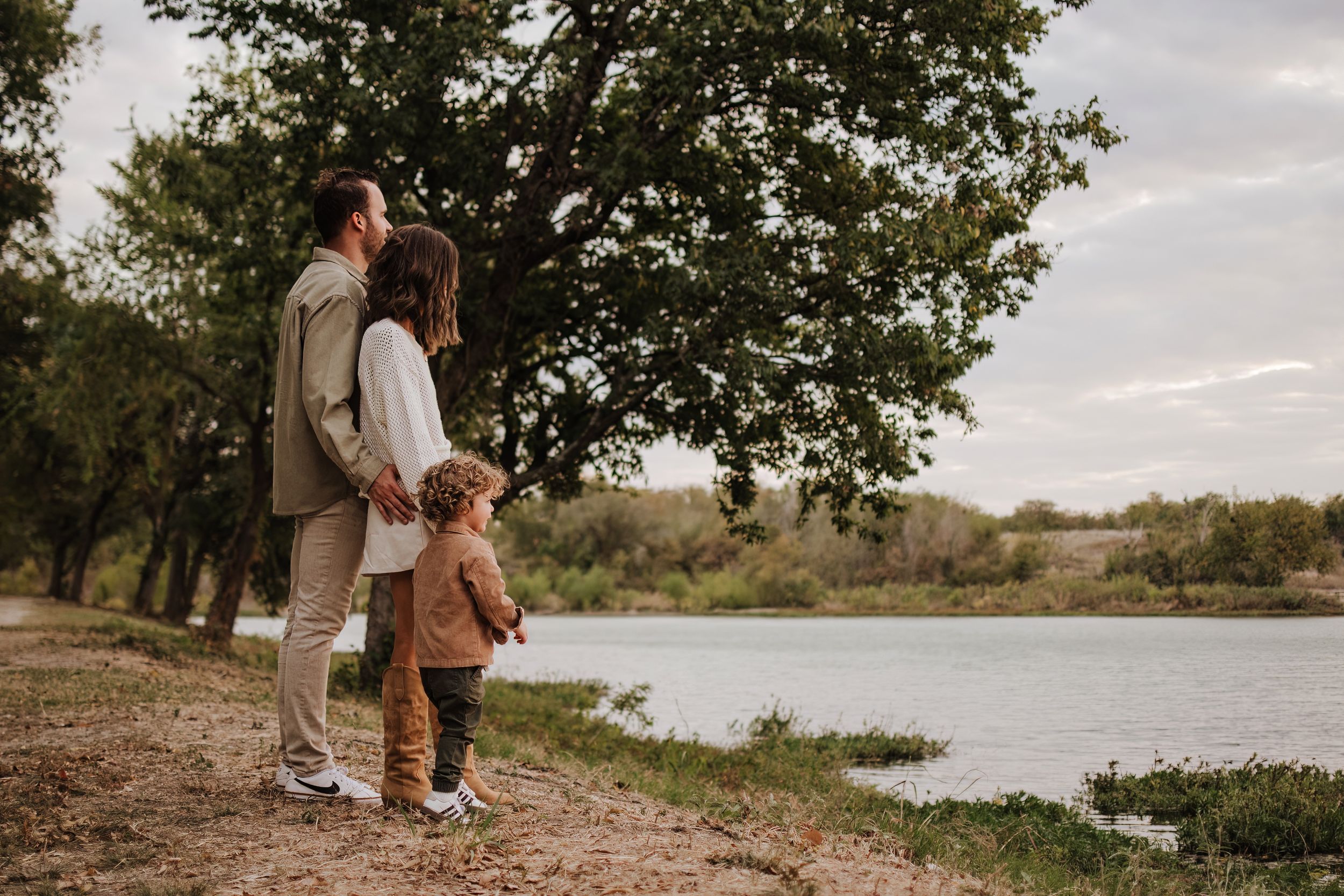 Three people walking together along a peaceful lakeside path during golden hour.