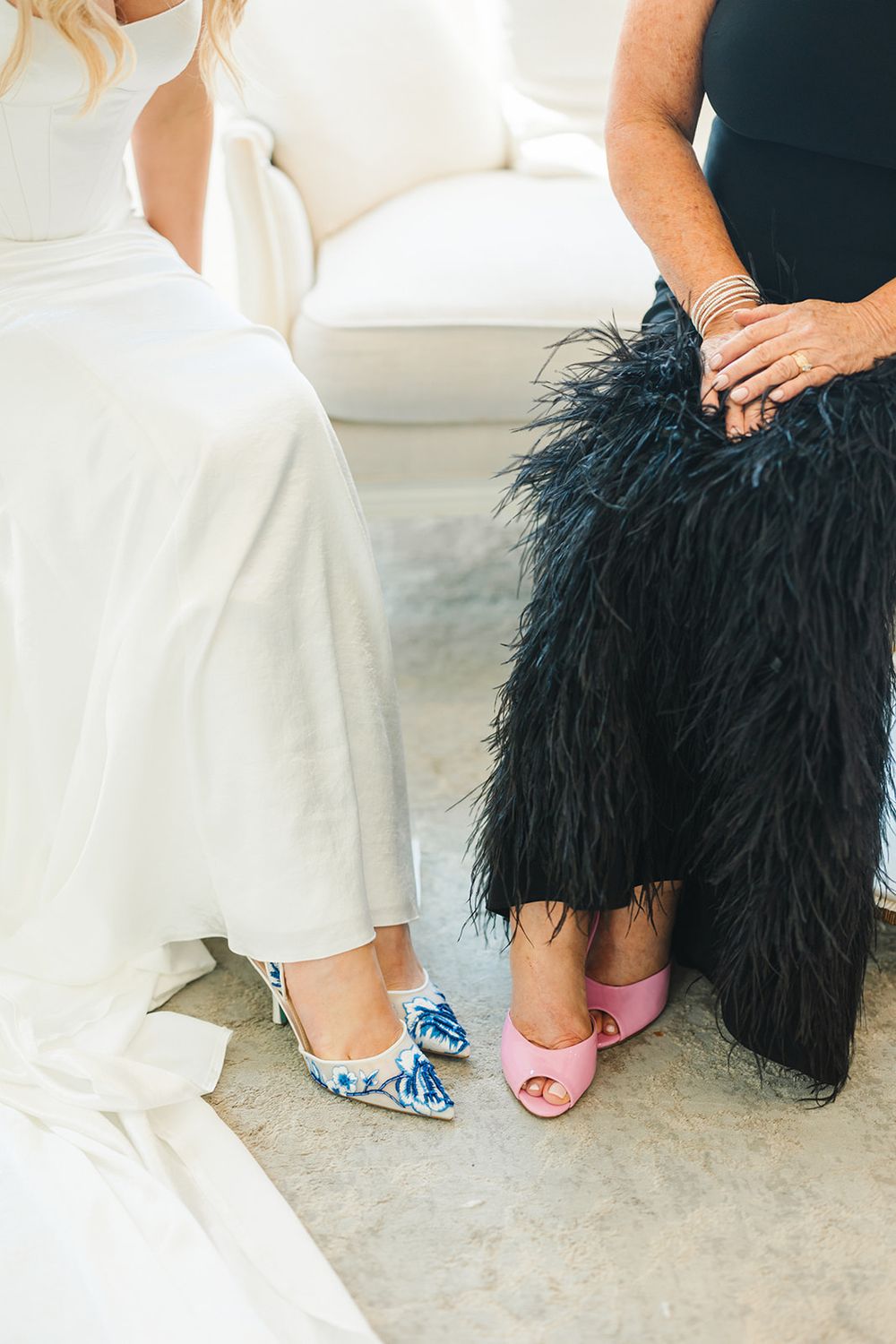 Two people sitting together wearing contrasting outfits of white and black, showing colorful statement shoes at their feet.