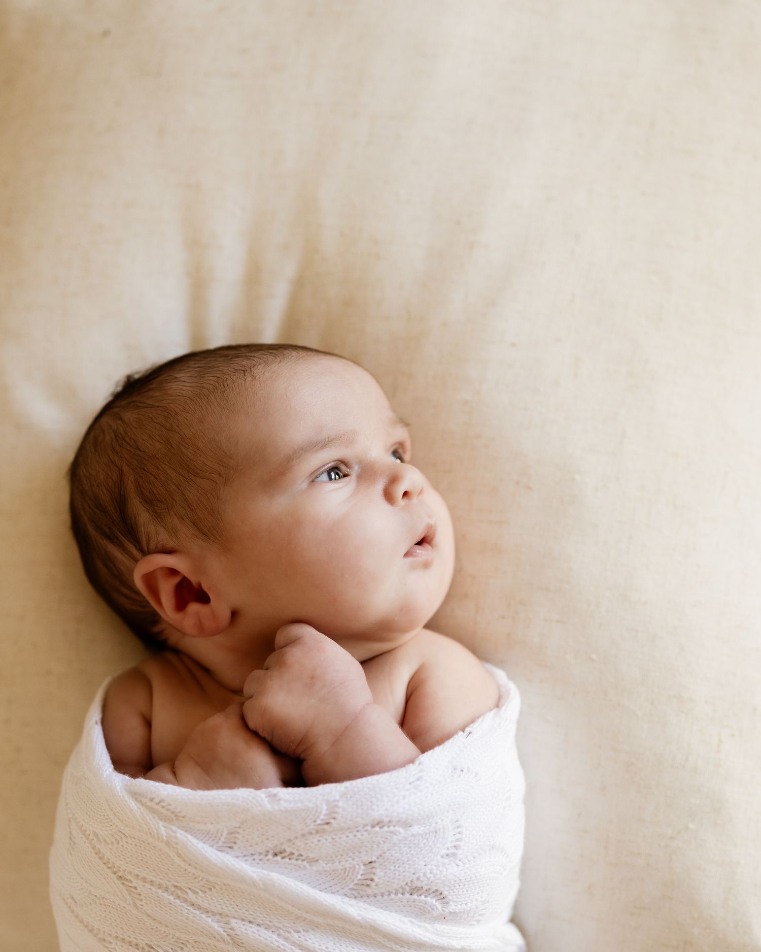 Baby wrapped in neutral blanket, photographed naturally in family’s living room in St Ives