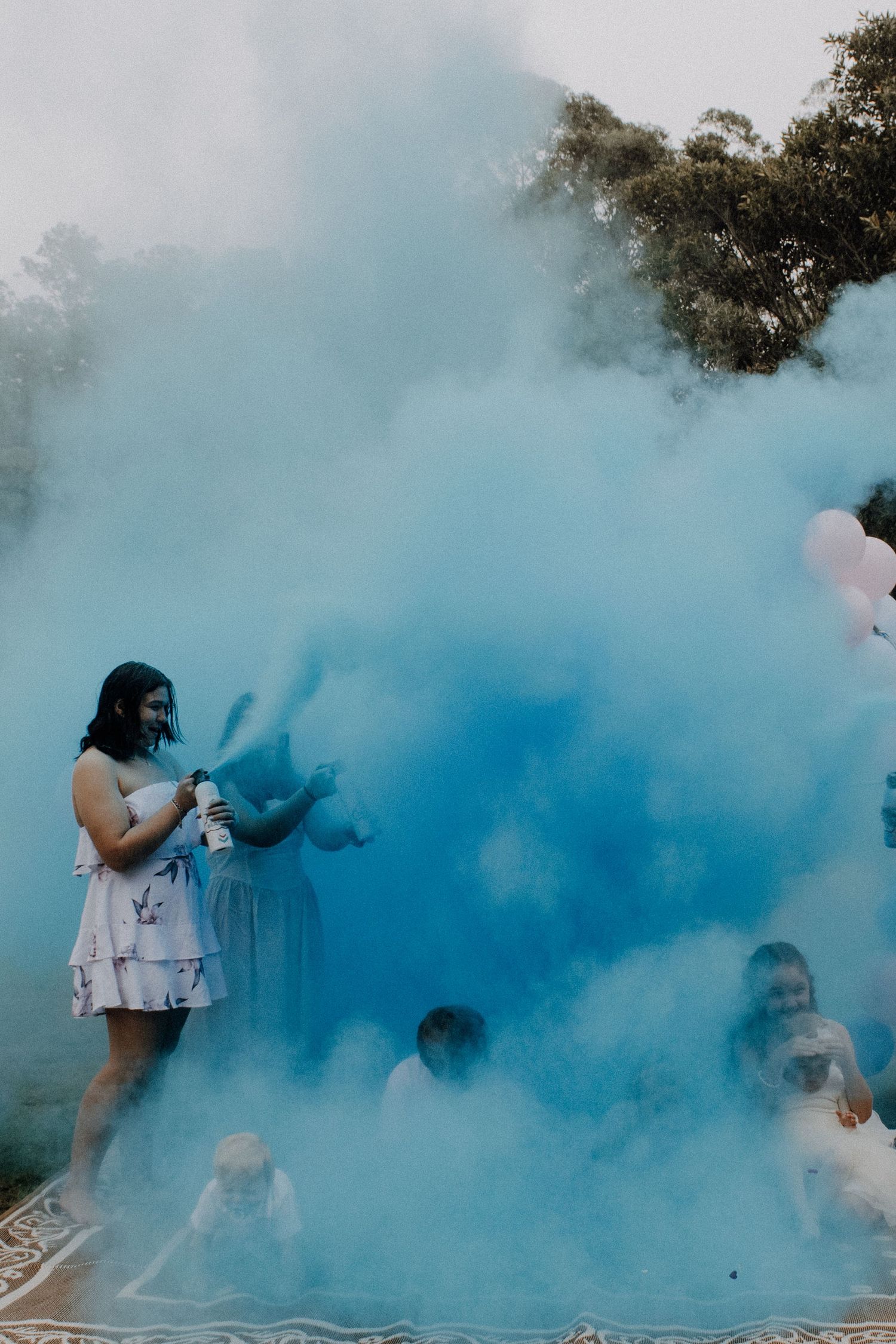 People surrounded by vibrant blue smoke during a colorful outdoor celebration or event.