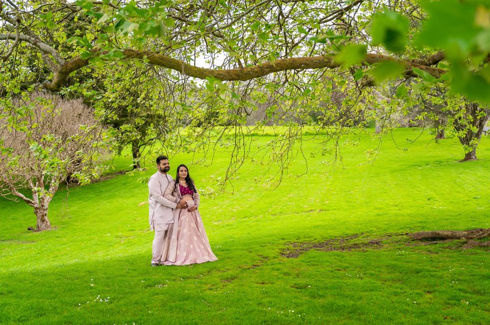 Figures in elegant pink floral dresses pose gracefully in a lush green garden setting during a special occasion.