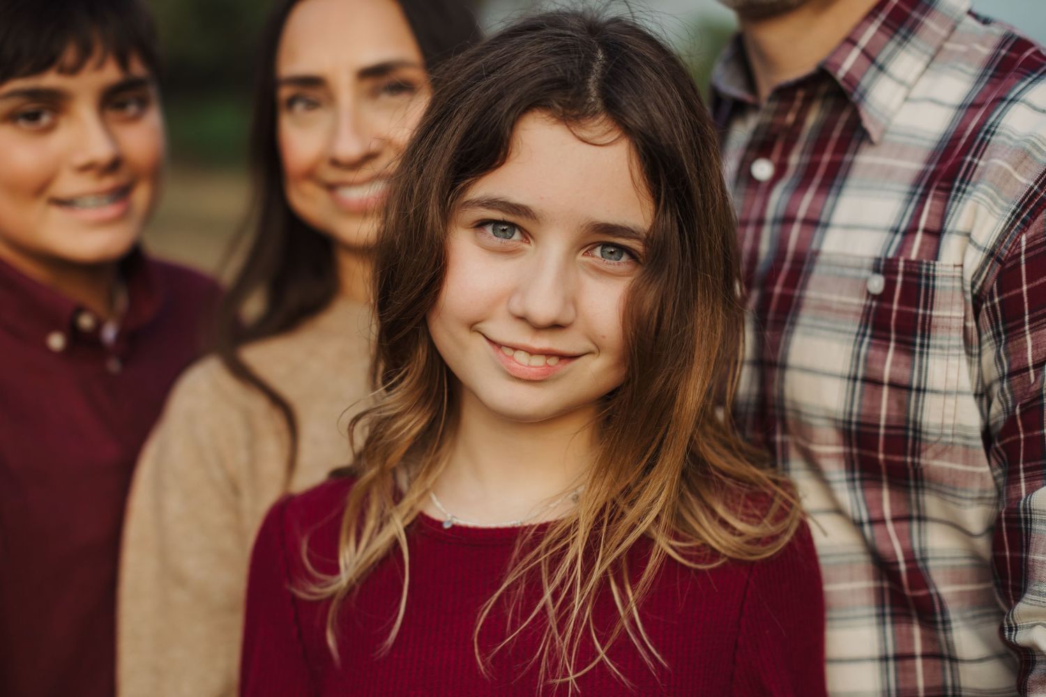 Smiling individuals with autumn-colored plaid shirts and sweaters pose together outdoors in natural afternoon light.