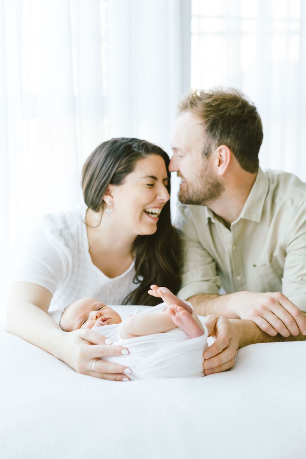 Couple sharing an intimate moment while looking at their newborn baby.