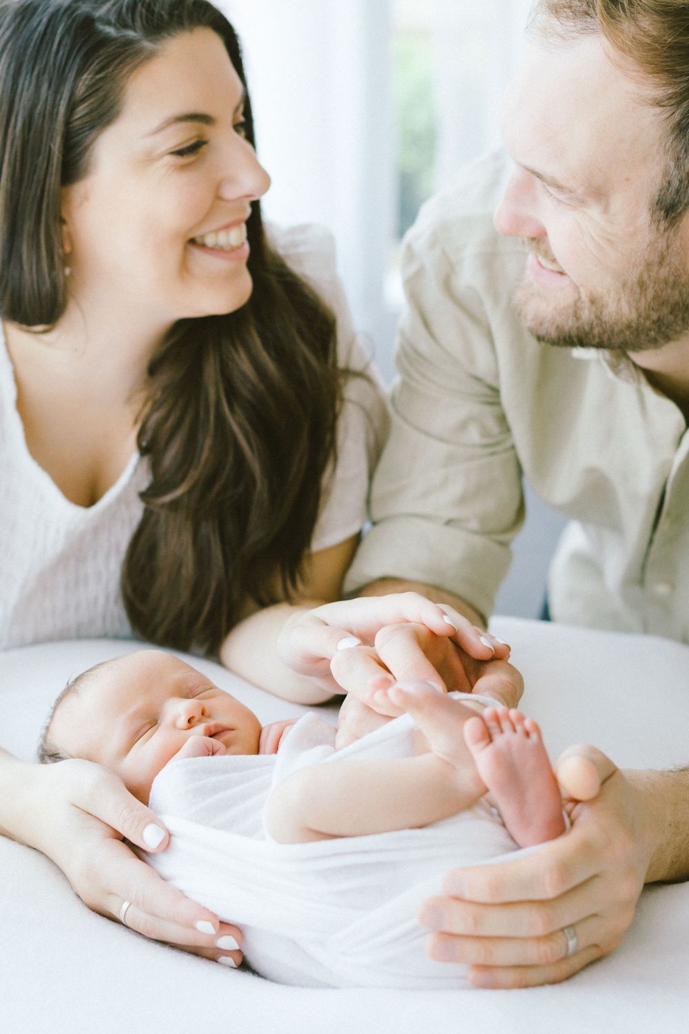 Joyful parents sharing tender moment with their newborn baby.
