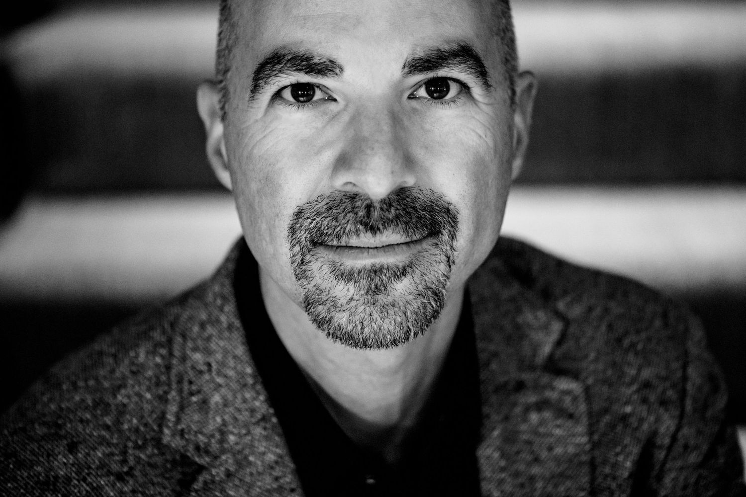 Black and white portrait of a professional man with facial hair wearing a dark sweater.