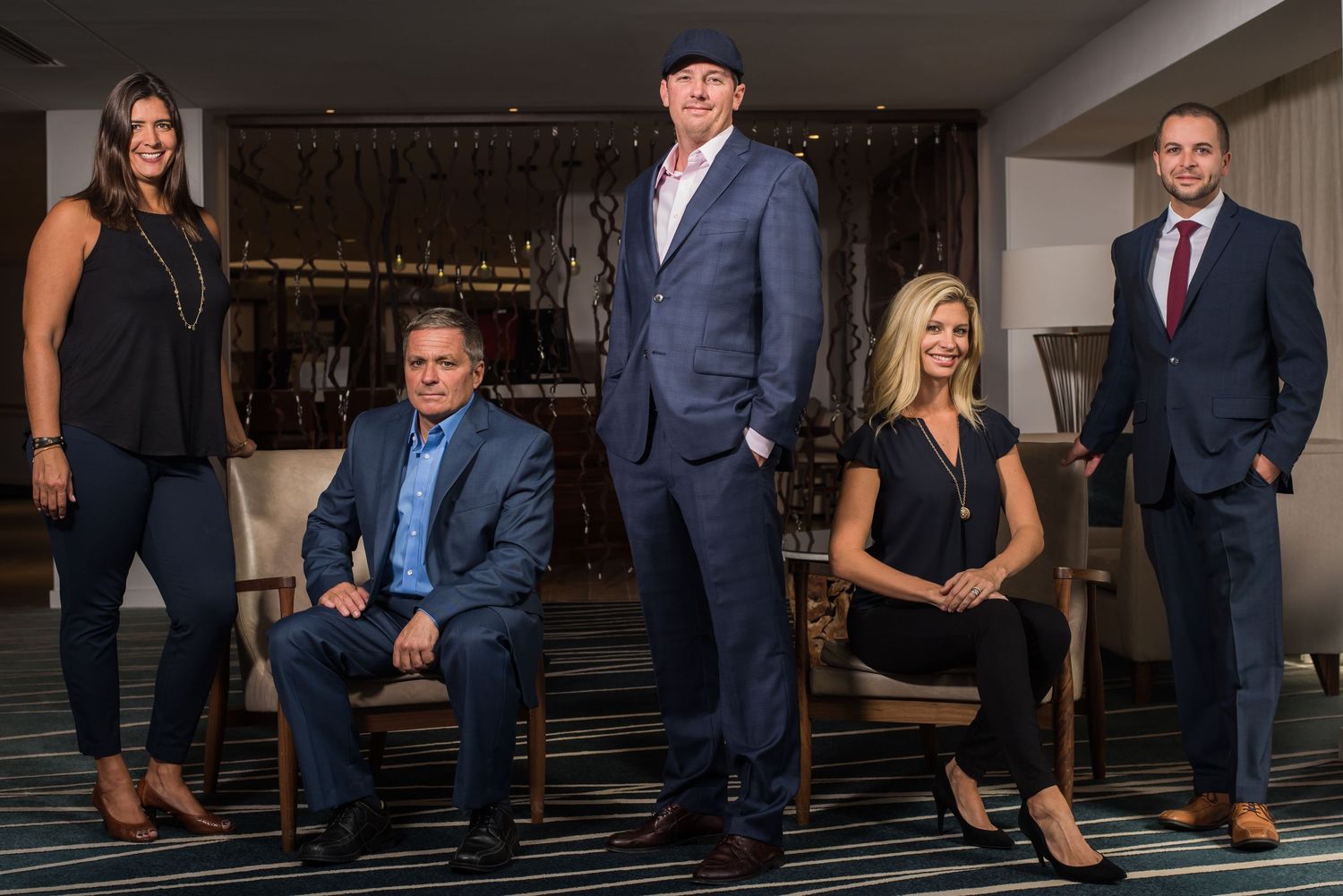 Business team of five professionals posed together in modern office setting.