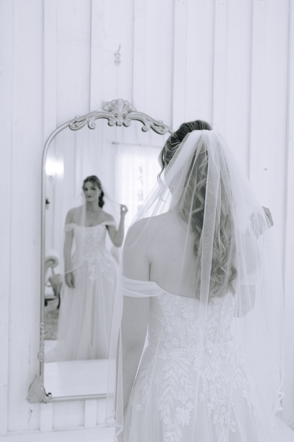Bridal reflections in vintage-style mirrors against a white paneled wall.