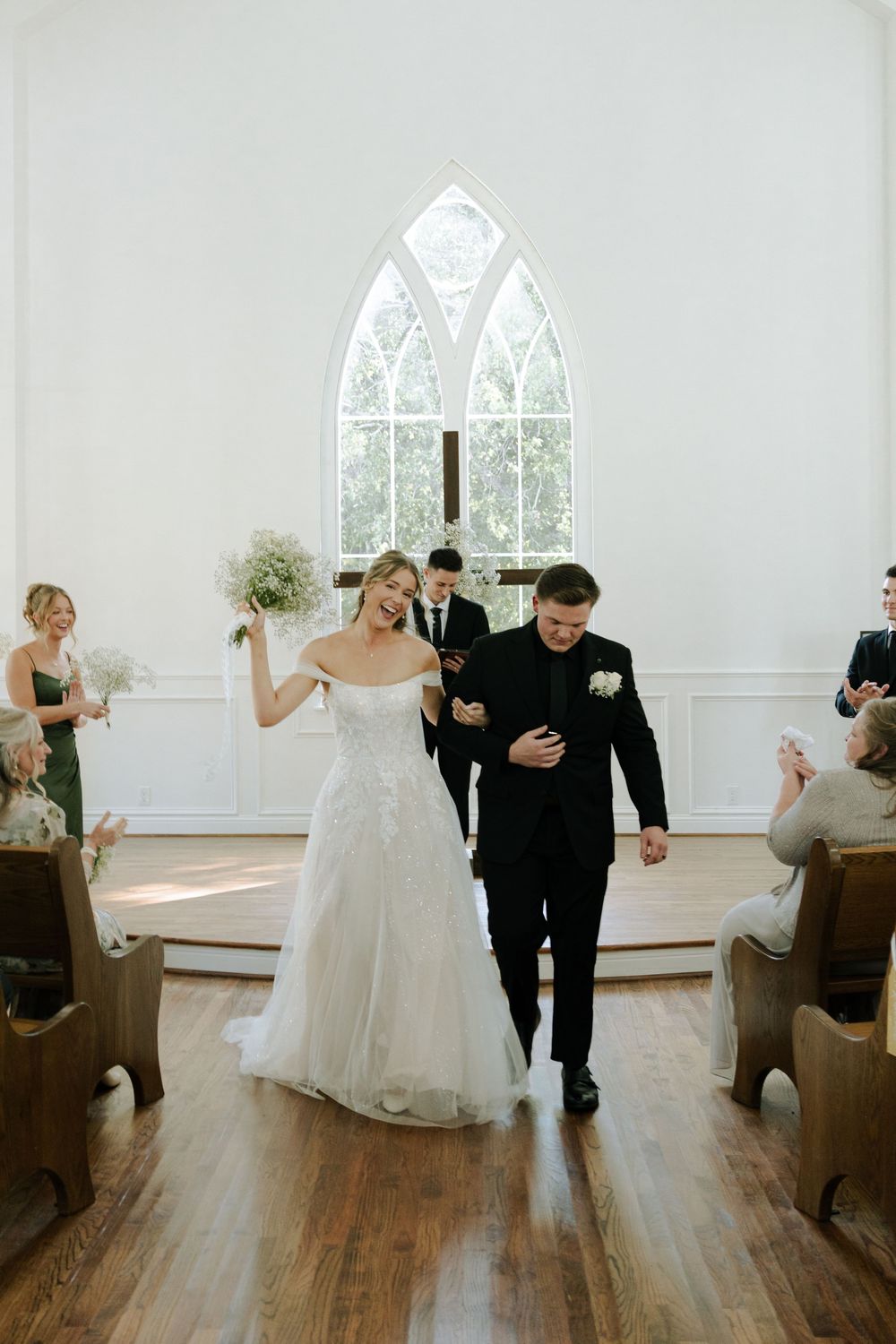 A couple walking down the aisle of a chapel after their wedding ceremony.