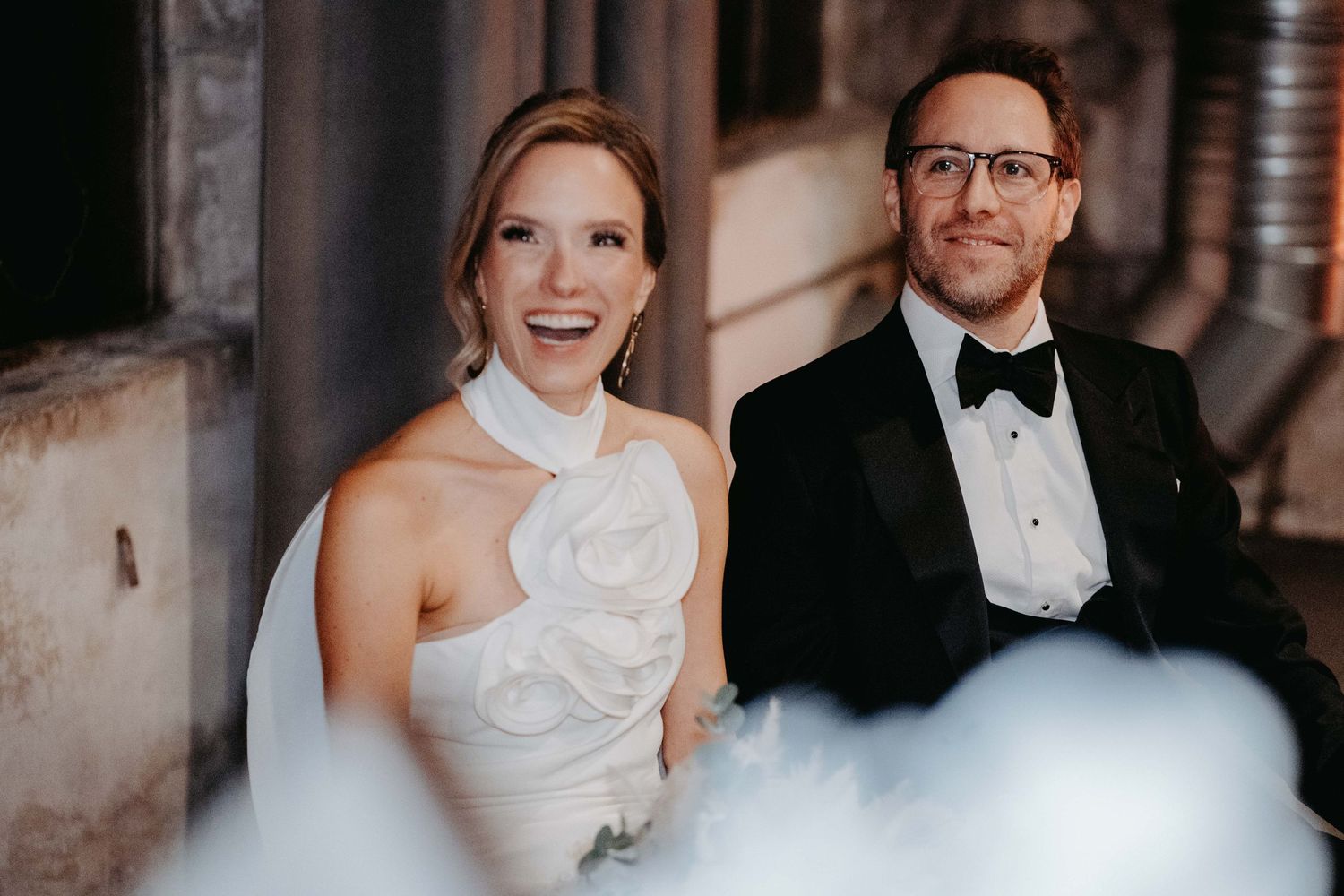 A happy wedding couple in formal wedding attire posed together, with the bride in a white gown and groom in a tuxedo.