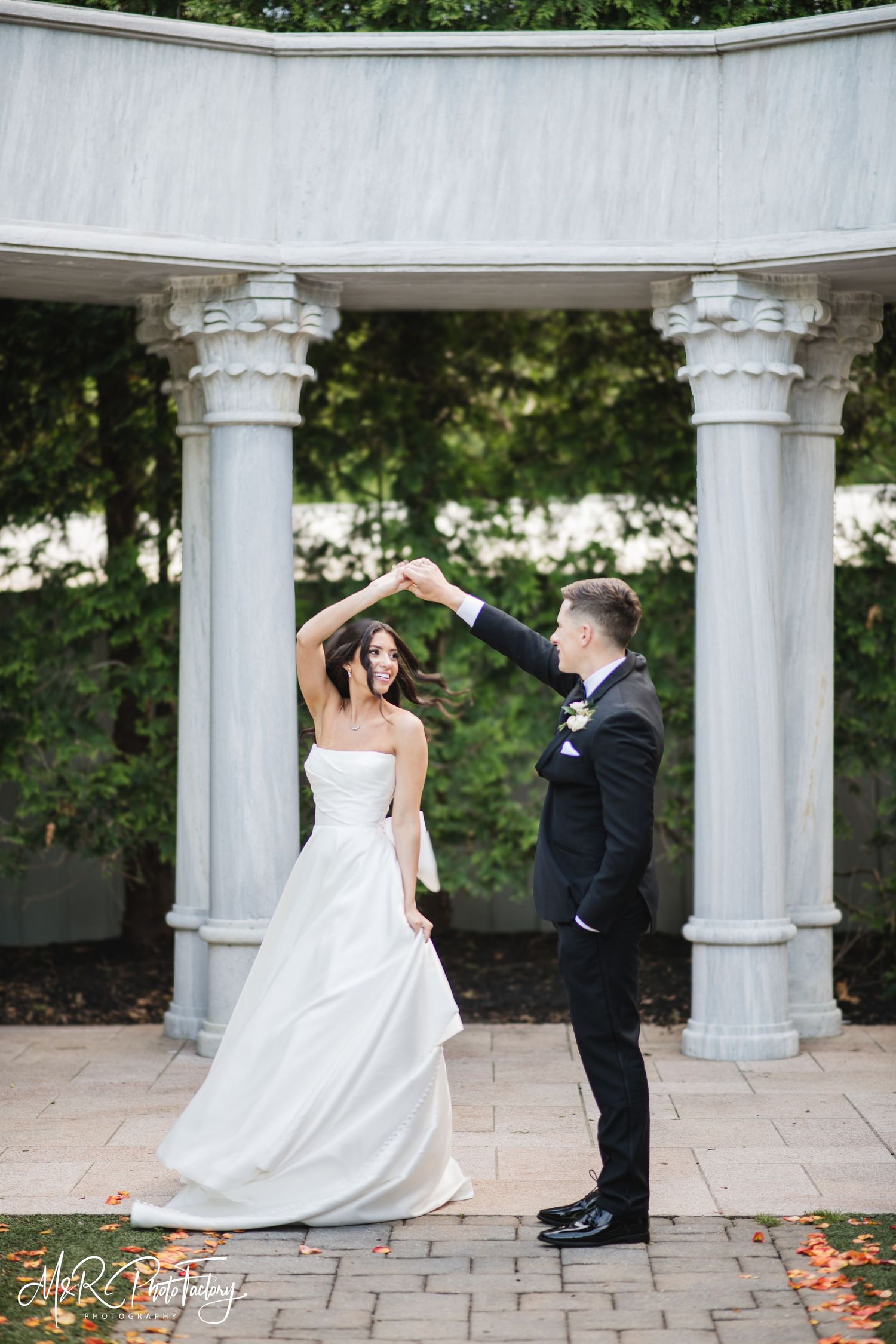 Bride and groom share a romantic dance under an elegant marble column rotunda during wedding portraits.