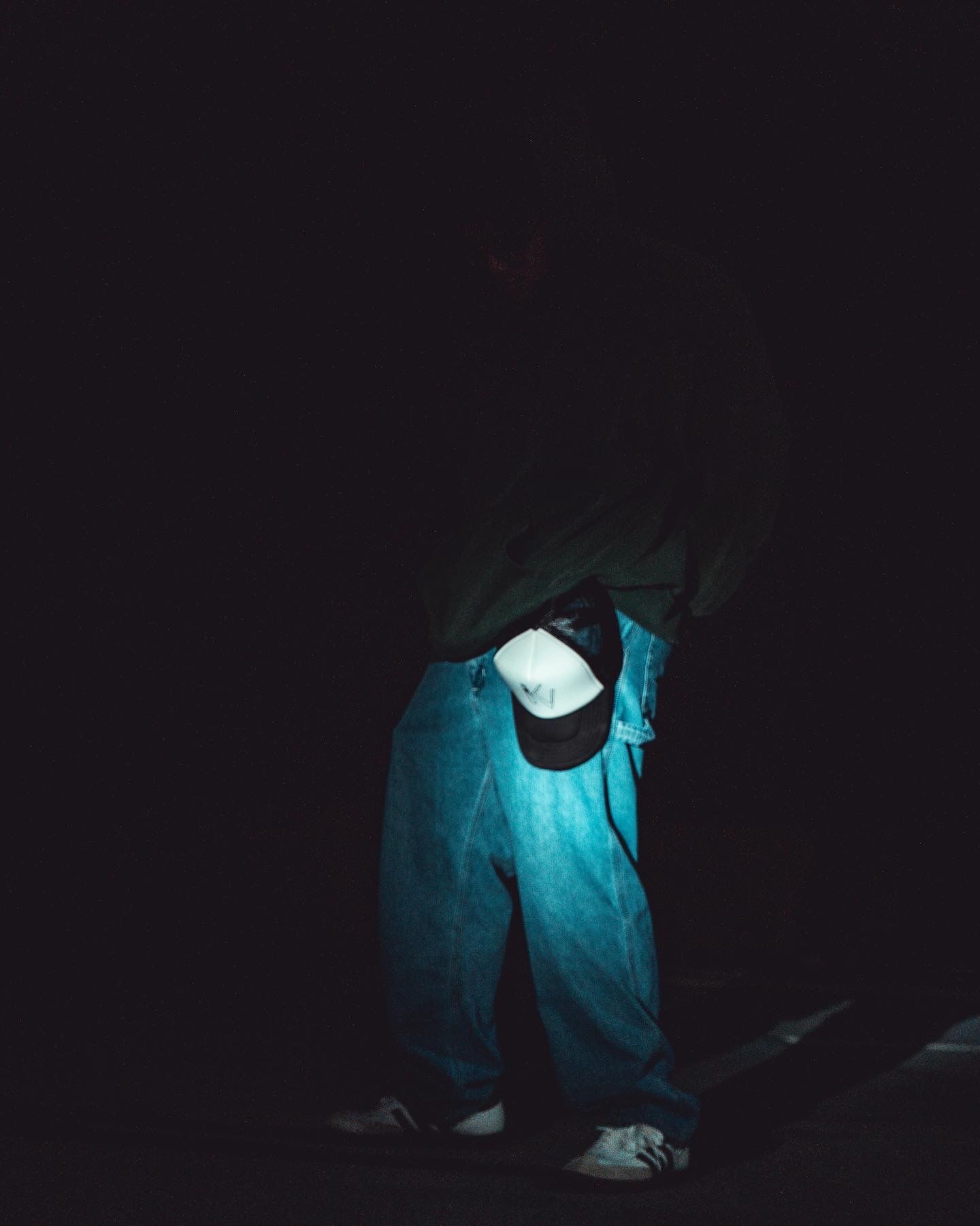 Person illuminated by blue light in dark environment looking at electronic device.