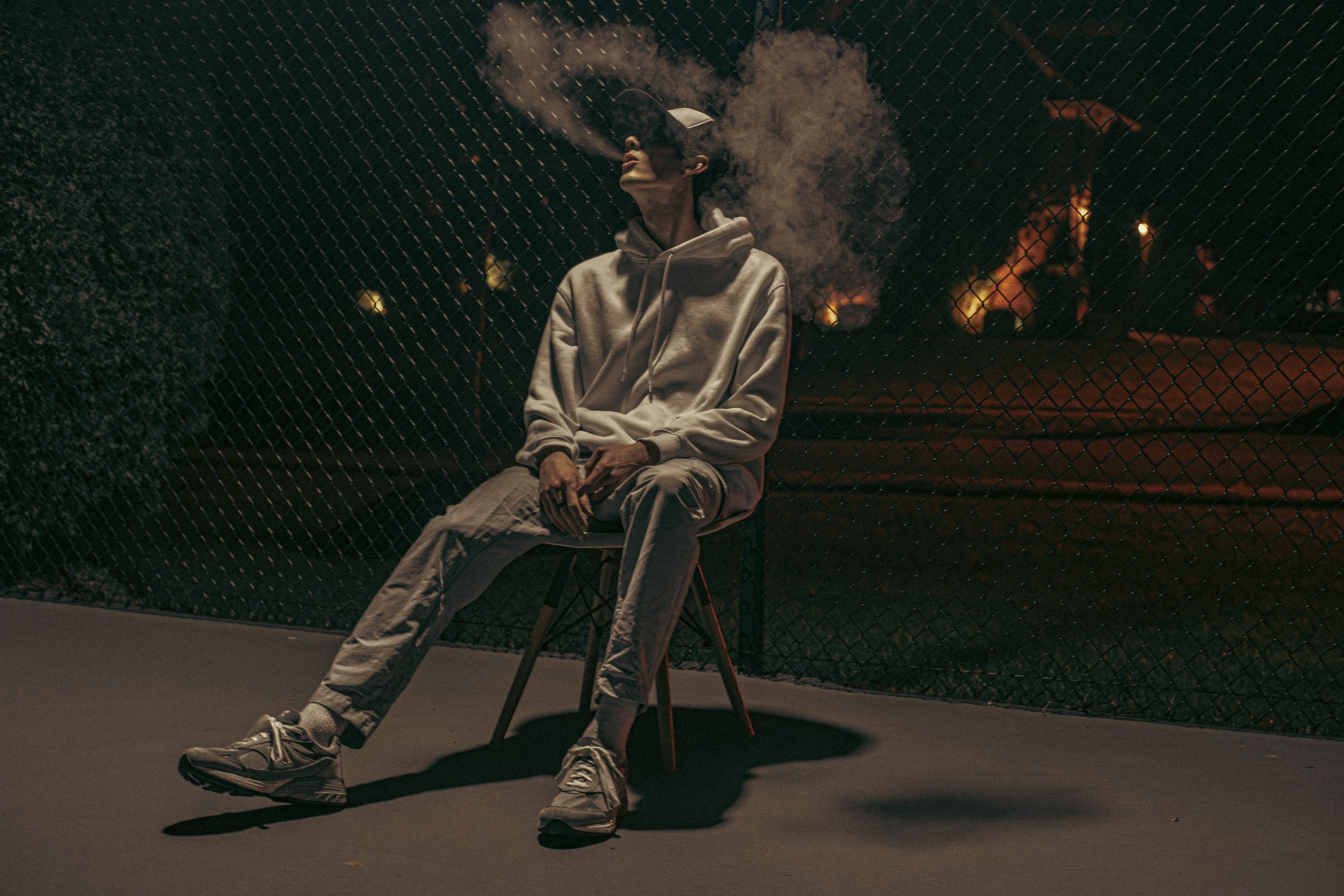 Dark atmospheric shots of person sitting against textured wall at night.
