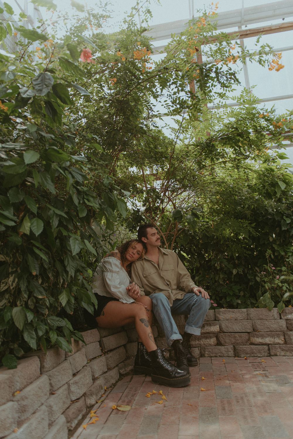 A couple sitting together in a greenhouse.