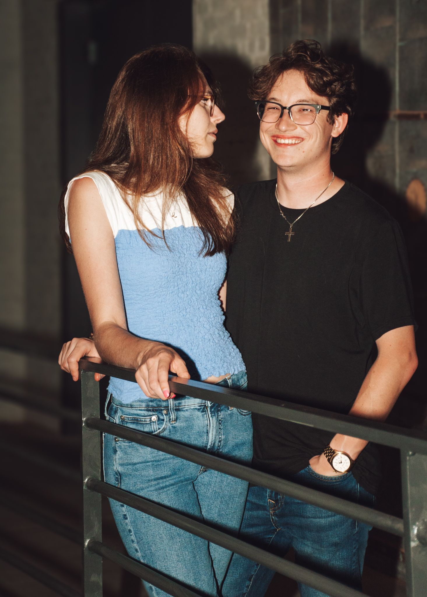 A candid moment of two people sharing a conversation while leaning on a railing.