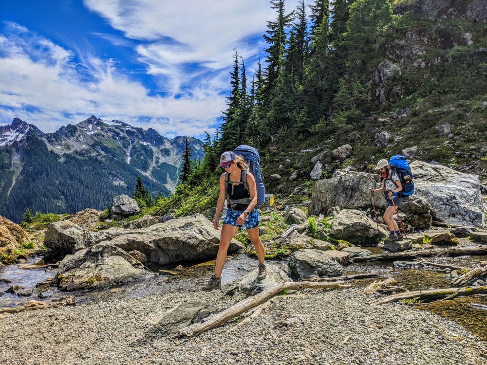 Two hikers crossing stream