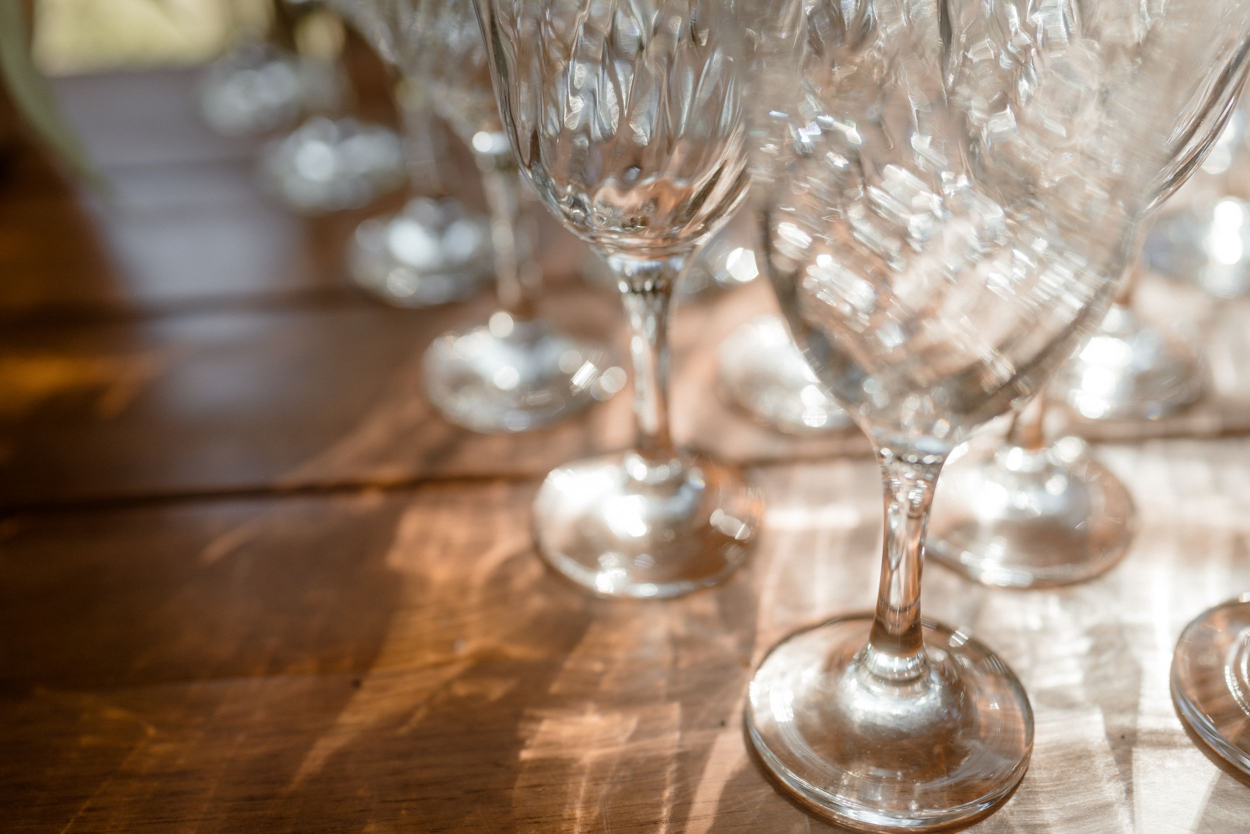 Crystal wine glasses arranged on a wooden table with soft focus lighting.