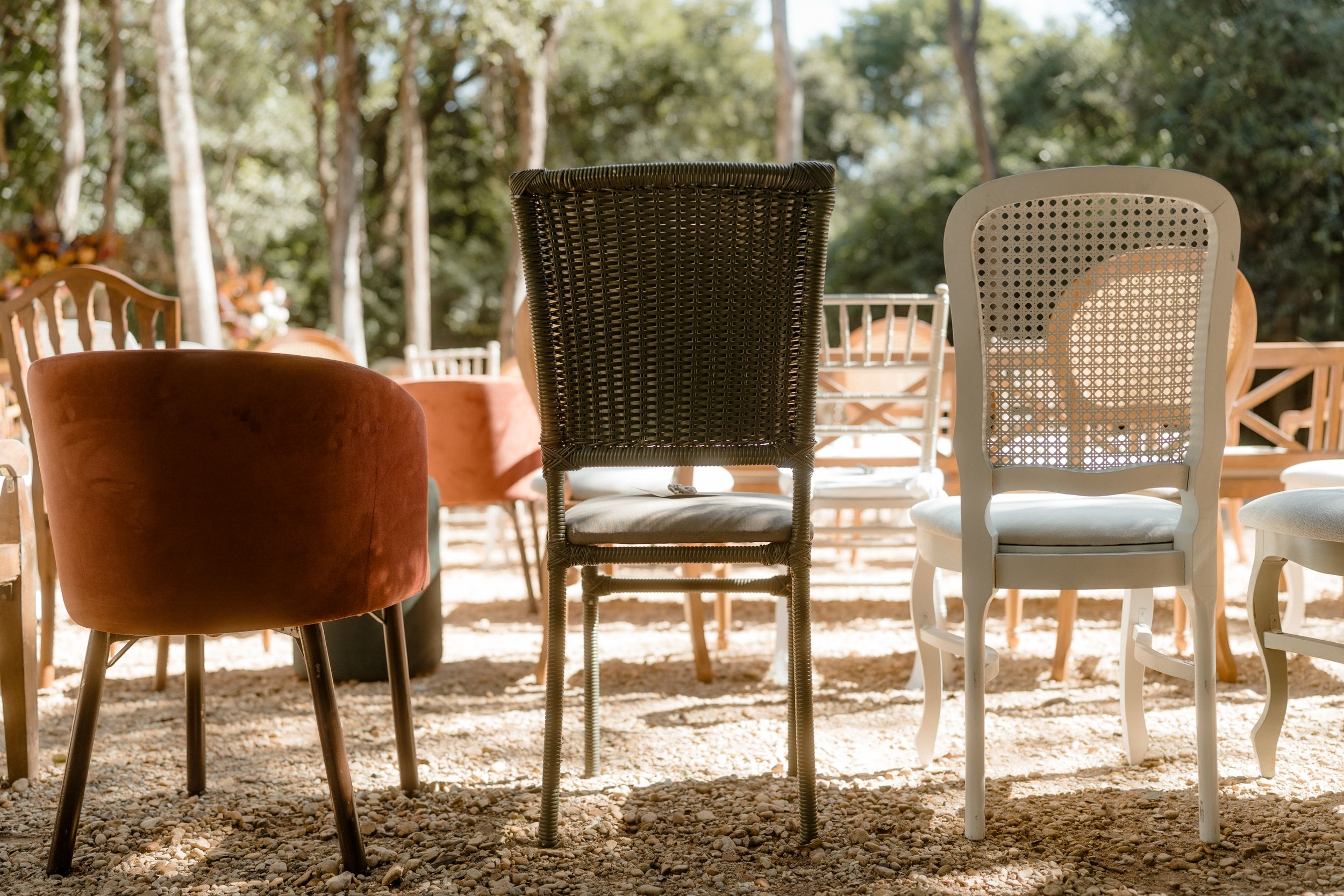 Eclectic mix of vintage chairs set up outdoors for a garden event.