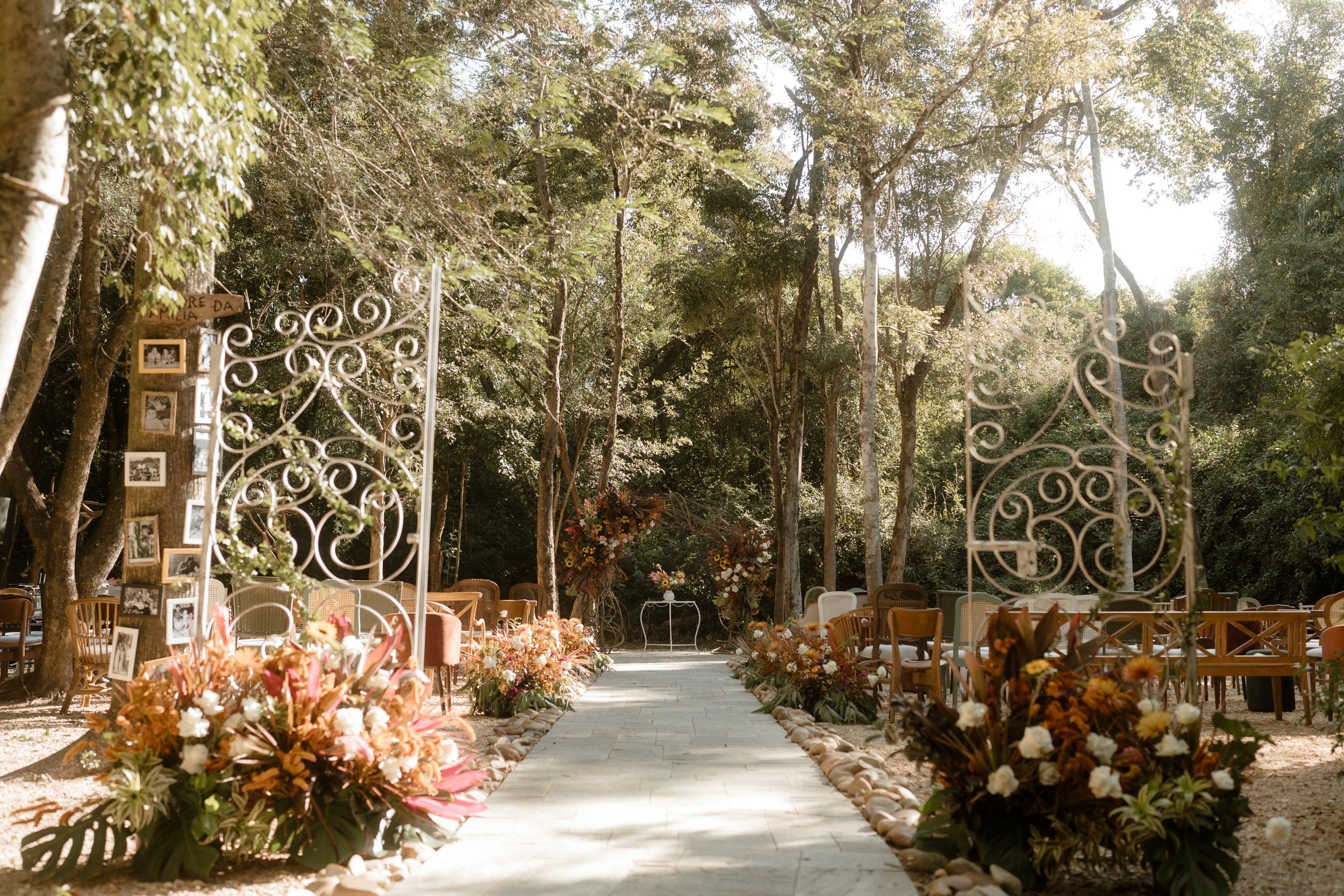 Outdoor wedding aisle decorated with ornate floral arrangements and rustic signage.