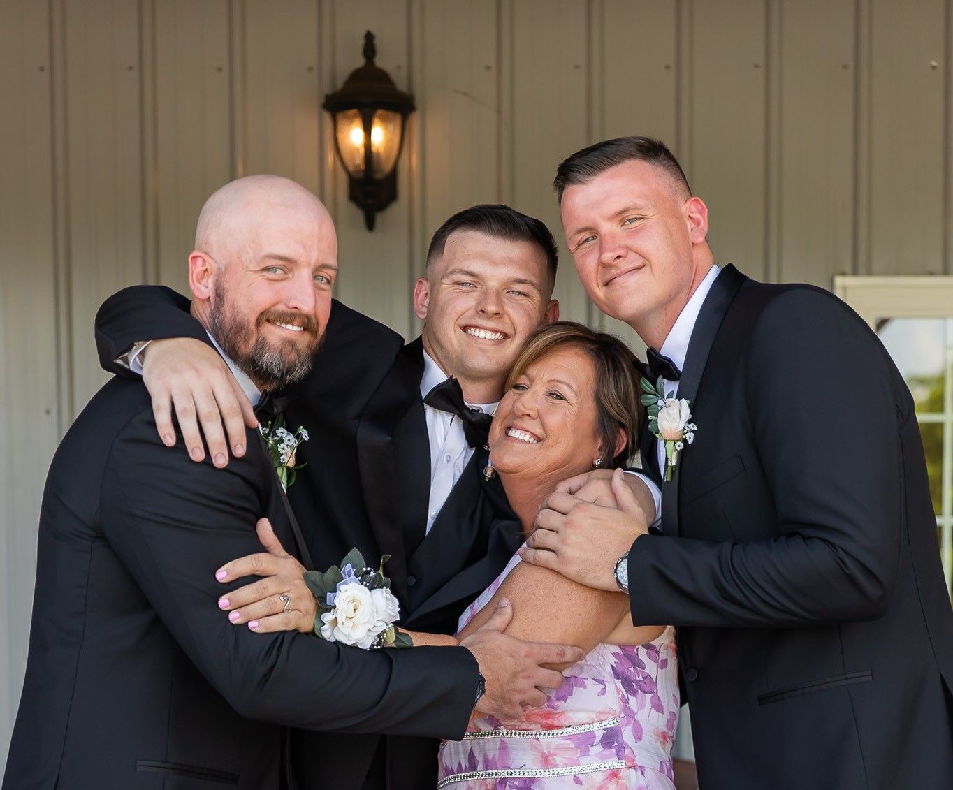 Wedding party sharing candid laughs on porch with vintage lantern lighting.
