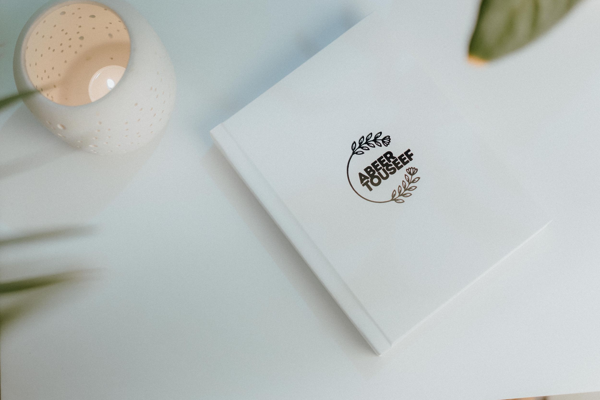 A minimalist white card with a small circular wreath logo.