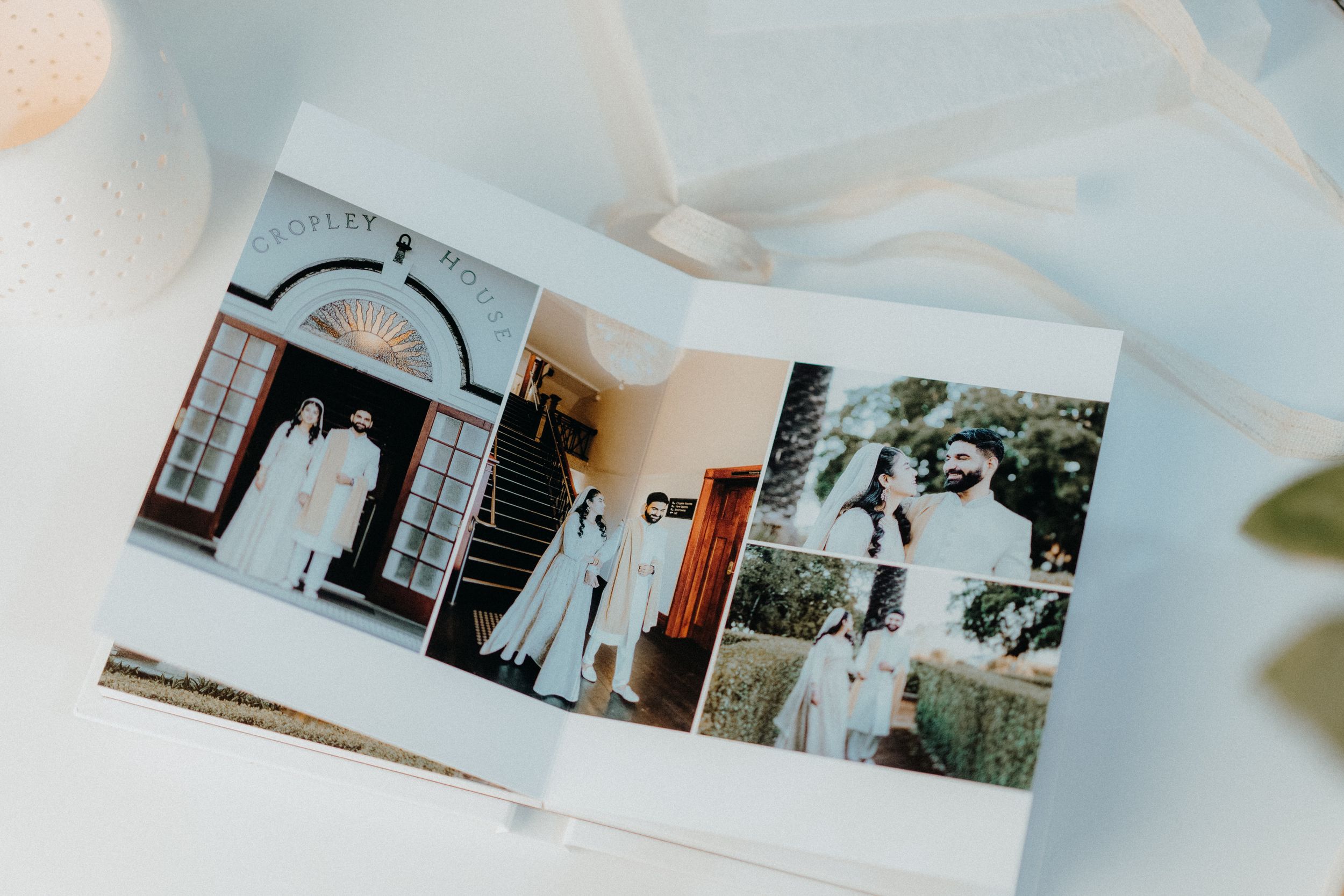 An open wedding album displaying professional photographs of ceremony and venue.