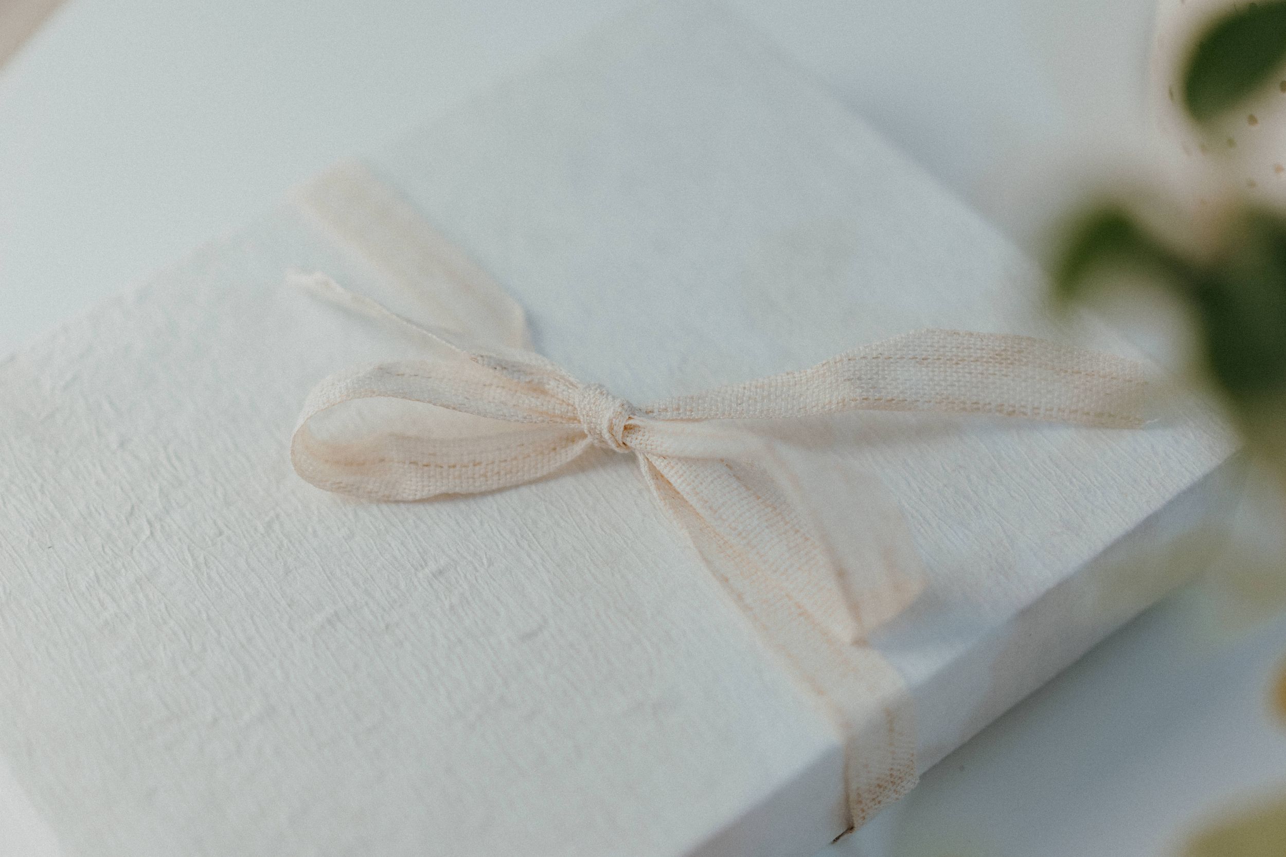 A white gift box tied with an elegant beige silk bow.