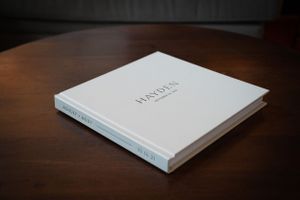 White professional photo album with minimal text design on dark wooden table.