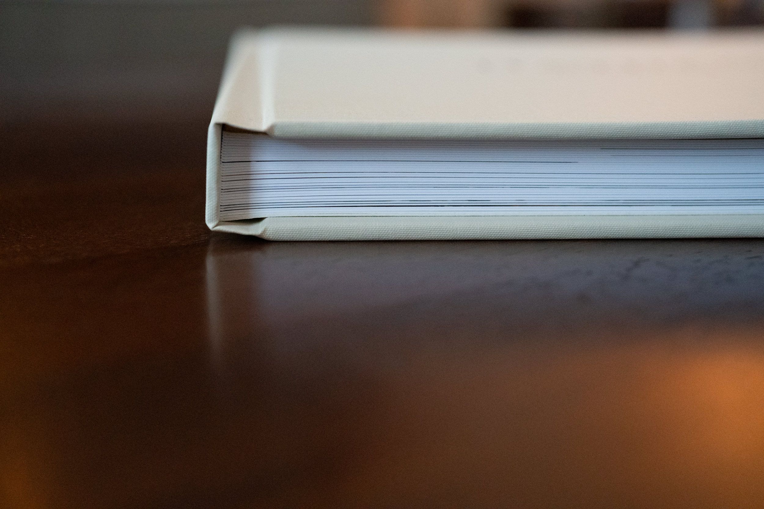 Side view of thick white photo album showing layered page edges.