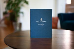 Navy blue luxury photo album with gold embossed logo on wooden table.