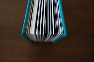Macro shot of teal book pages fanned out showing binding detail.