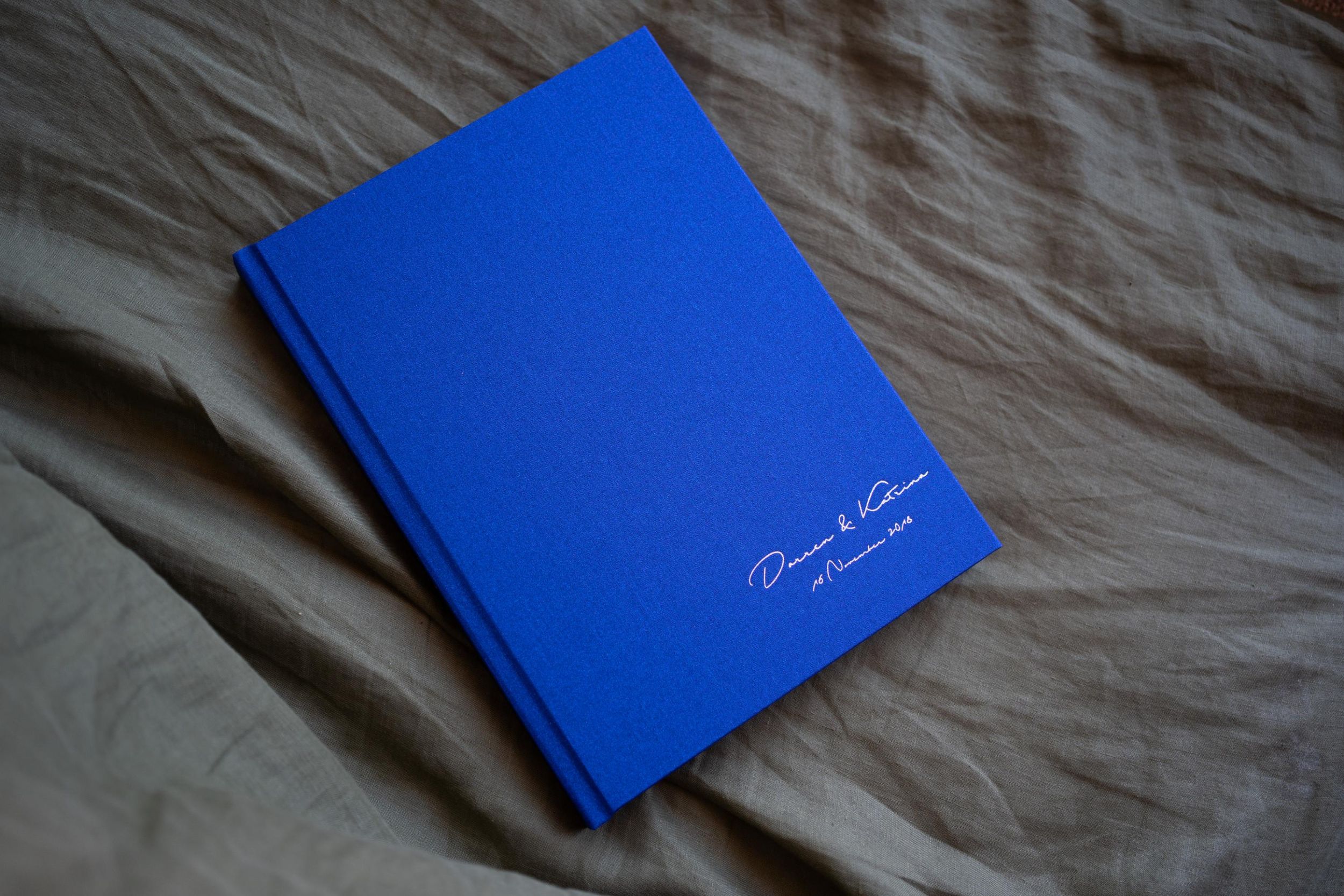 Simple blue hardcover book lying on textured fabric.