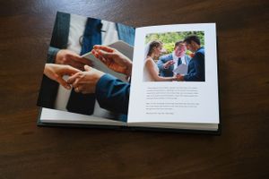 Open wedding album showing professional photography layout with ring exchange photo.