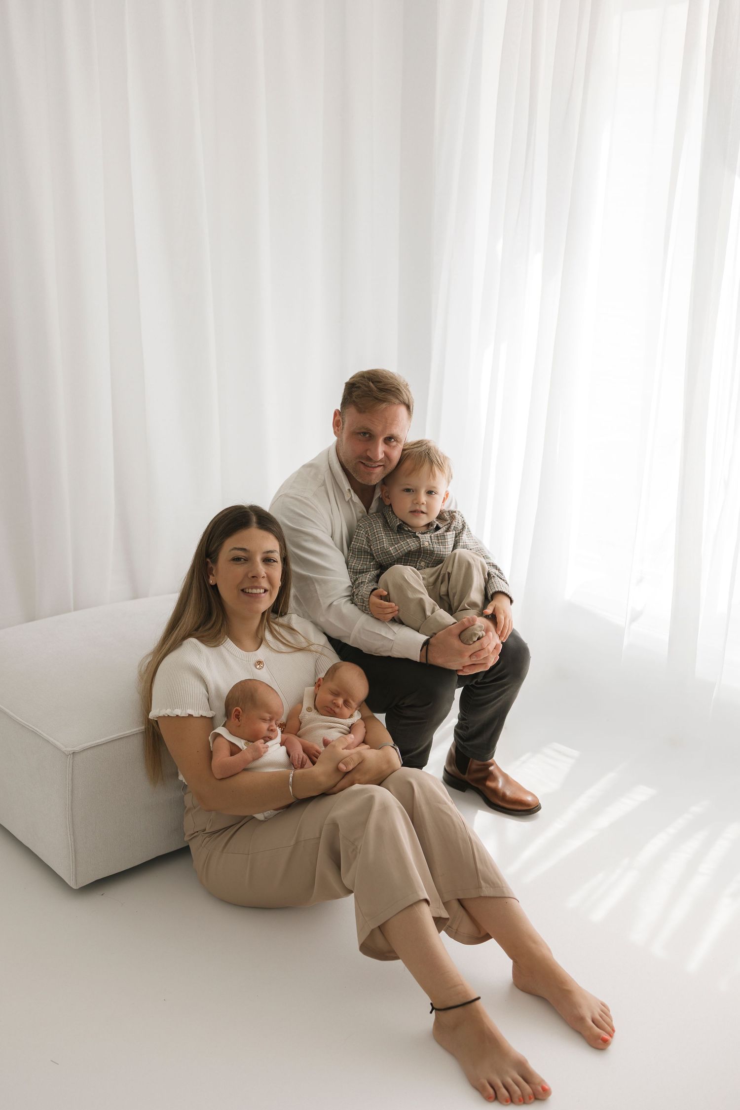 Family in white clothing sharing intimate moment together on bed.