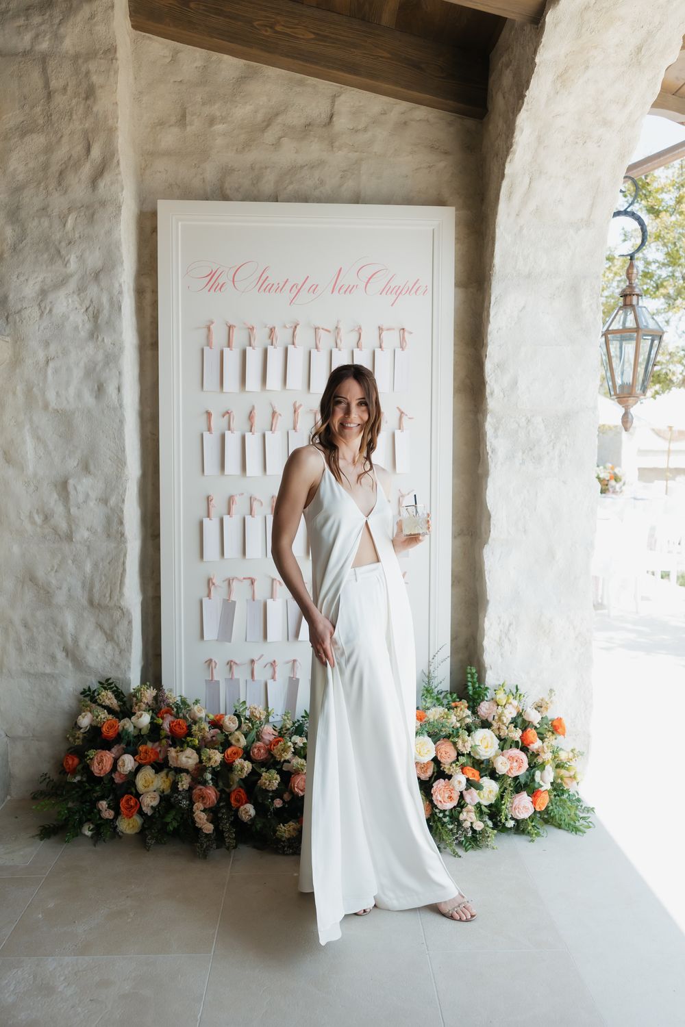 Bridal portrait session against white wall with floral decorations and seating chart display.