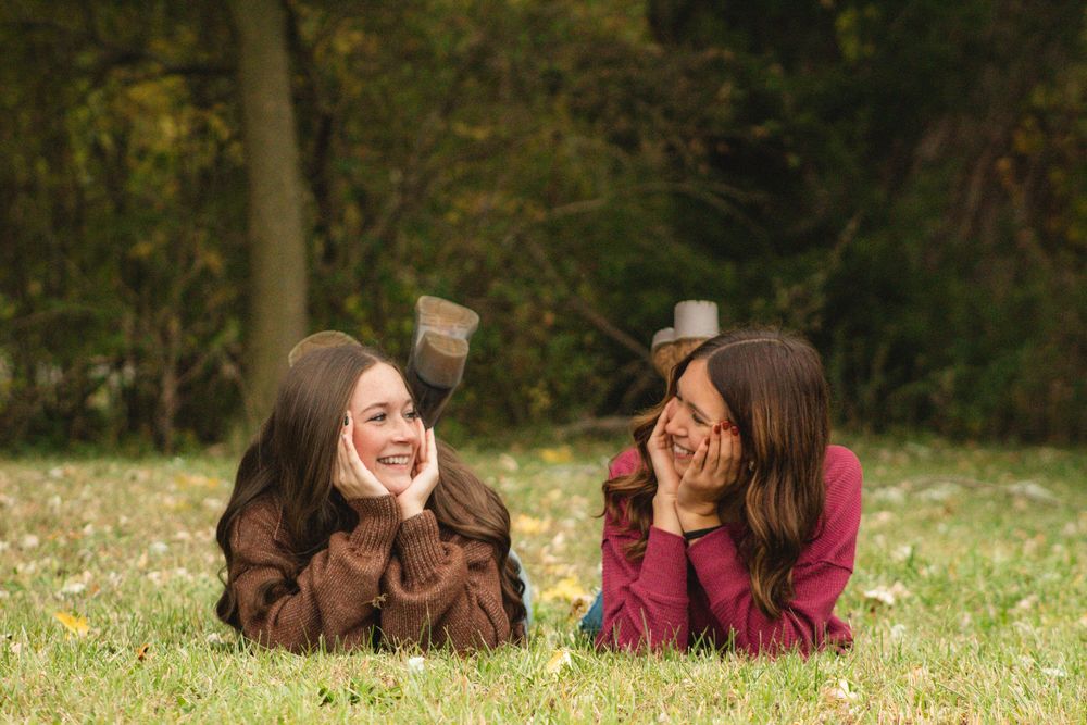 two friends laying in the grass looking at each other