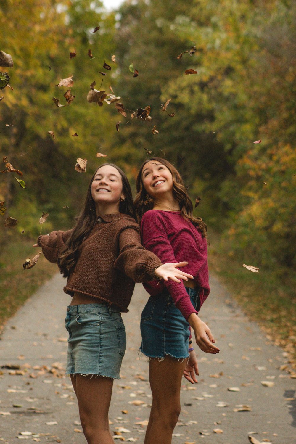 two friends throwing leaves in the air